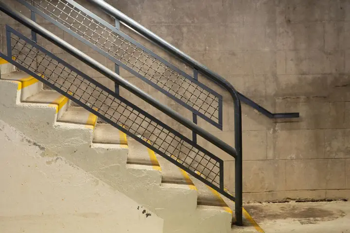 Concrete stairs with a metal handrail and mesh side panels