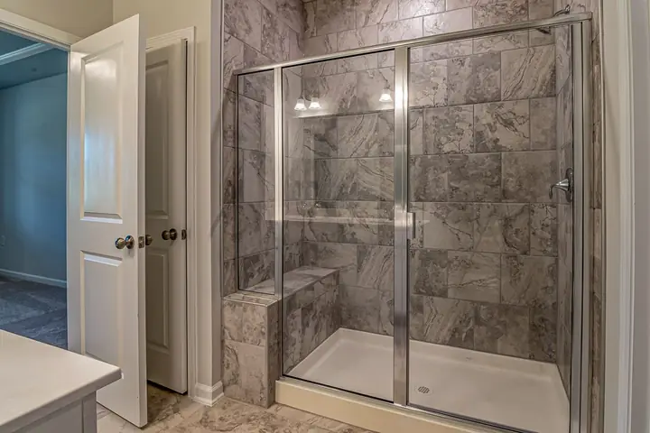 Glass shower door in a marble tiled shower