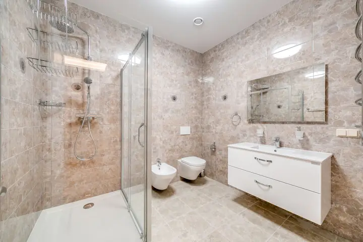 Glass shower, wall toilet and floating vanity in stone tile