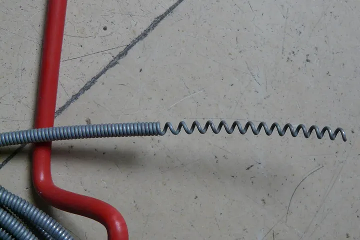 Coiled drain auger cable with a red crank
