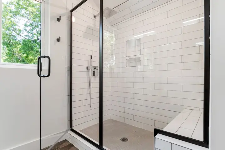 Black framed glass shower with white subway tile walls