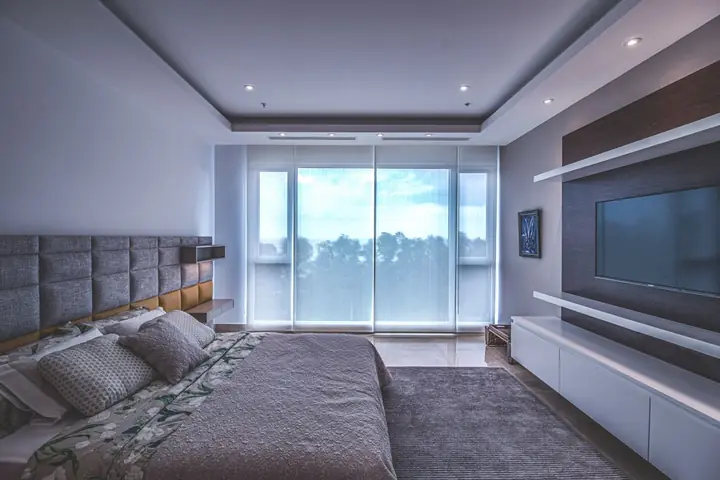 Bedroom with a wide window and a TV on the far wall