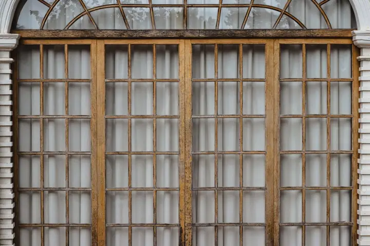 Classic wooden framed glass windows with closed white curtains, offering a blend of elegance and privacy