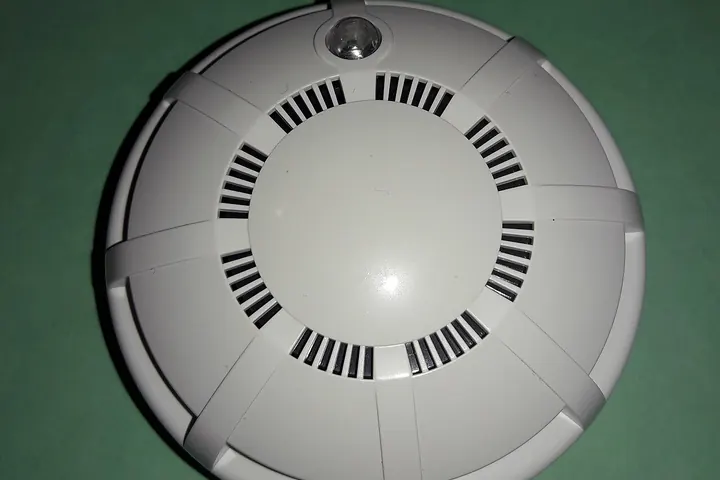 Round white smoke detector on a green background