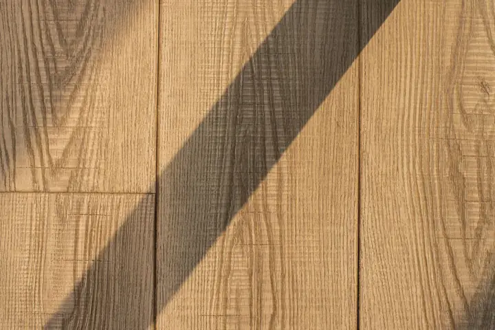 Detailed view of wooden floor planks with a dramatic shadow, showing natural texture
