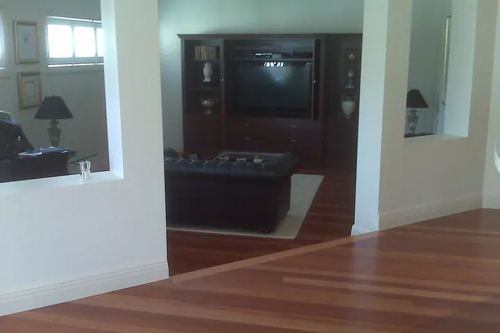 Hardwood floor running into a room with dark furniture