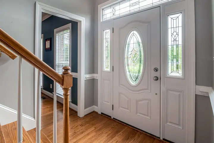 White front door with oval glass and side lights near stairs