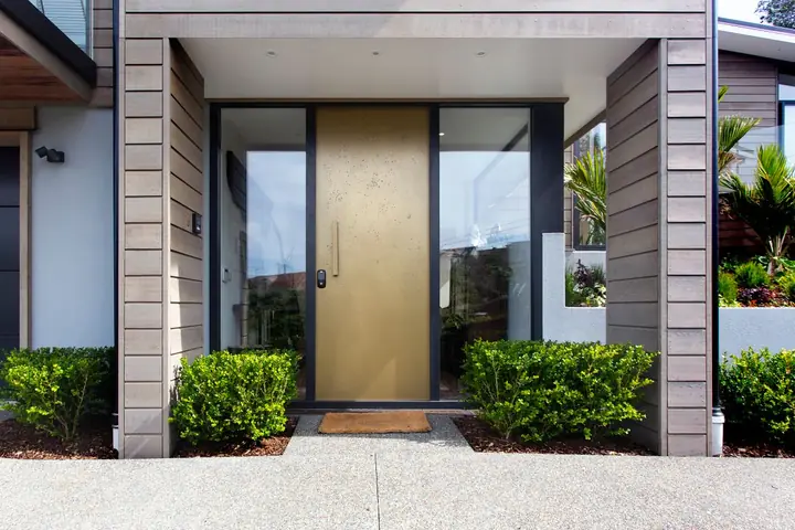 Wood front door with tall glass panels between stone columns