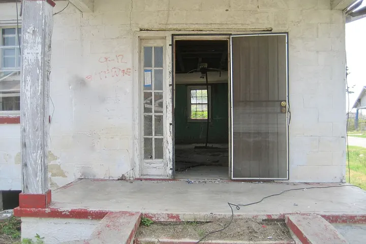 Metal storm door standing open on a concrete porch