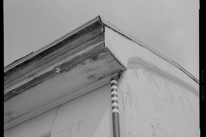 Stucco gable end below a weathered wood roof edge
