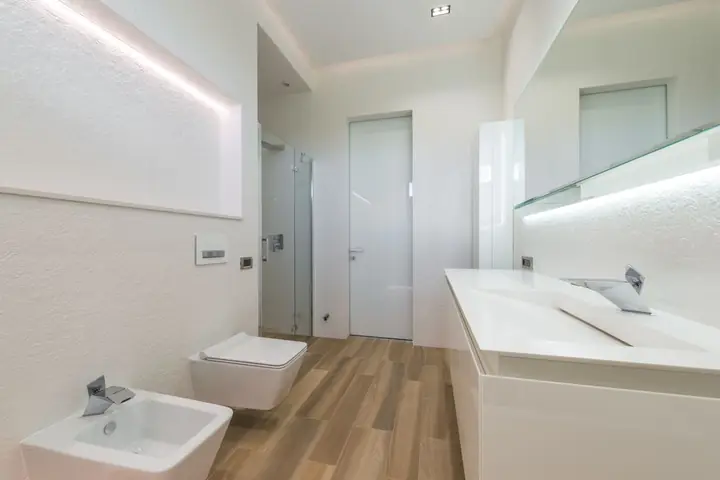 Bathroom with a built-in tub, wall toilet and wood floor
