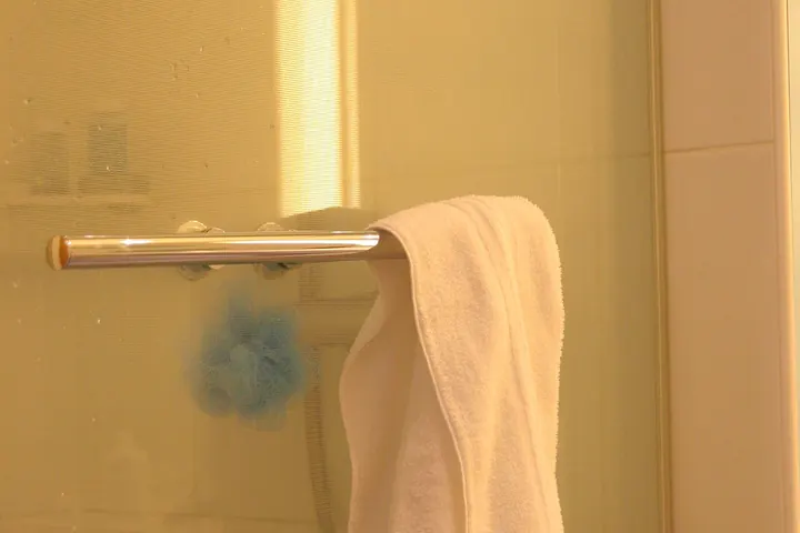 Towel hanging on a glass shower door bar