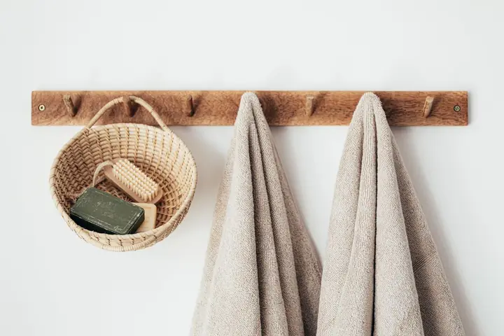 Wooden wall hanger with soft towels and wicker basket with natural spa cosmetics products