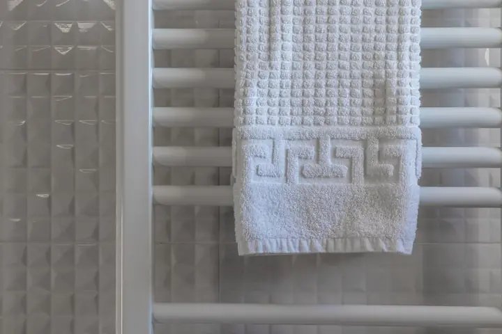 White towel draped on a chrome towel warmer