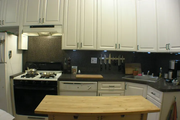 White kitchen cabinets with a black backsplash and under-cabinet lights