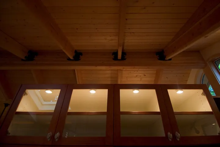 Glass-front cabinets lit from inside under a wood ceiling