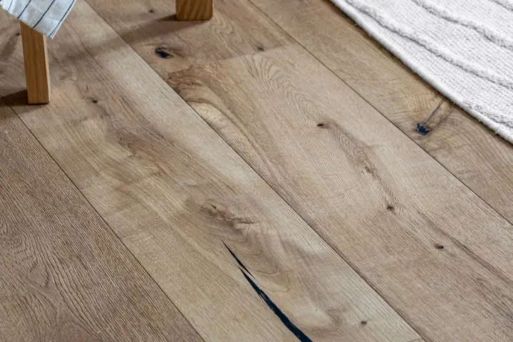 High angle view of natural wooden plank flooring next to a woven rug