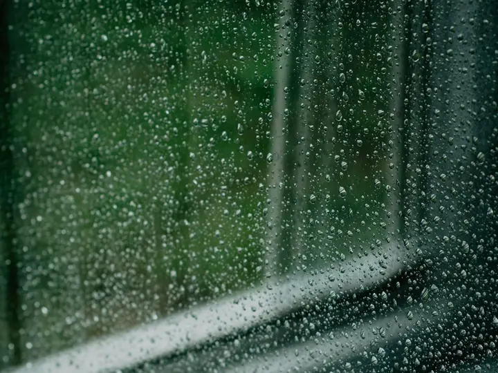 Close-up of a window with raindrops creating a soothing and melancholic atmosphere