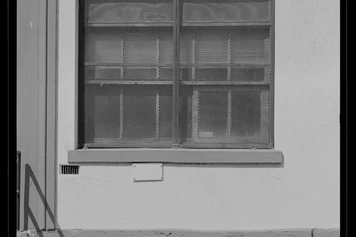 Window with a concrete sill in a plain stucco wall
