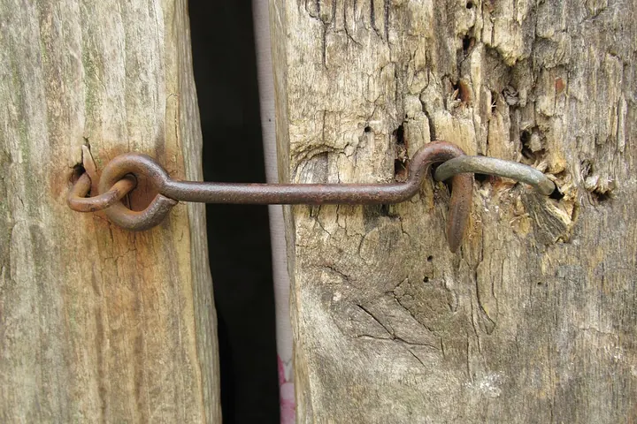 Rusty hook-and-eye latch on an old wooden frame