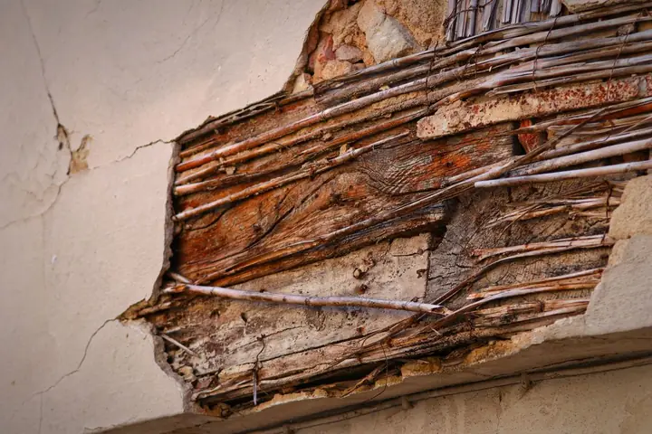 Detailed view of an old wall showing exposed wooden structure and cracks