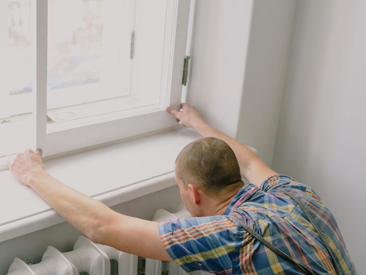 Handyman working at the sill of a tall white window